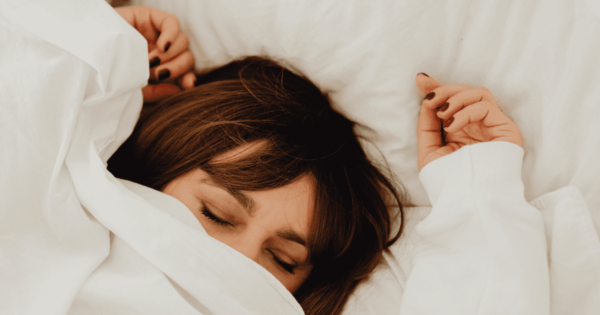 Nő csukott szemmel fekszik az ágyban